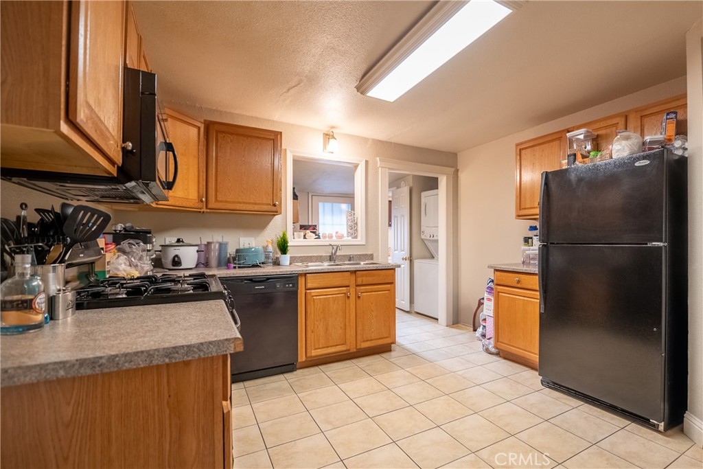 Kitchen with wood cabinets, tiled floor, and black appliances.