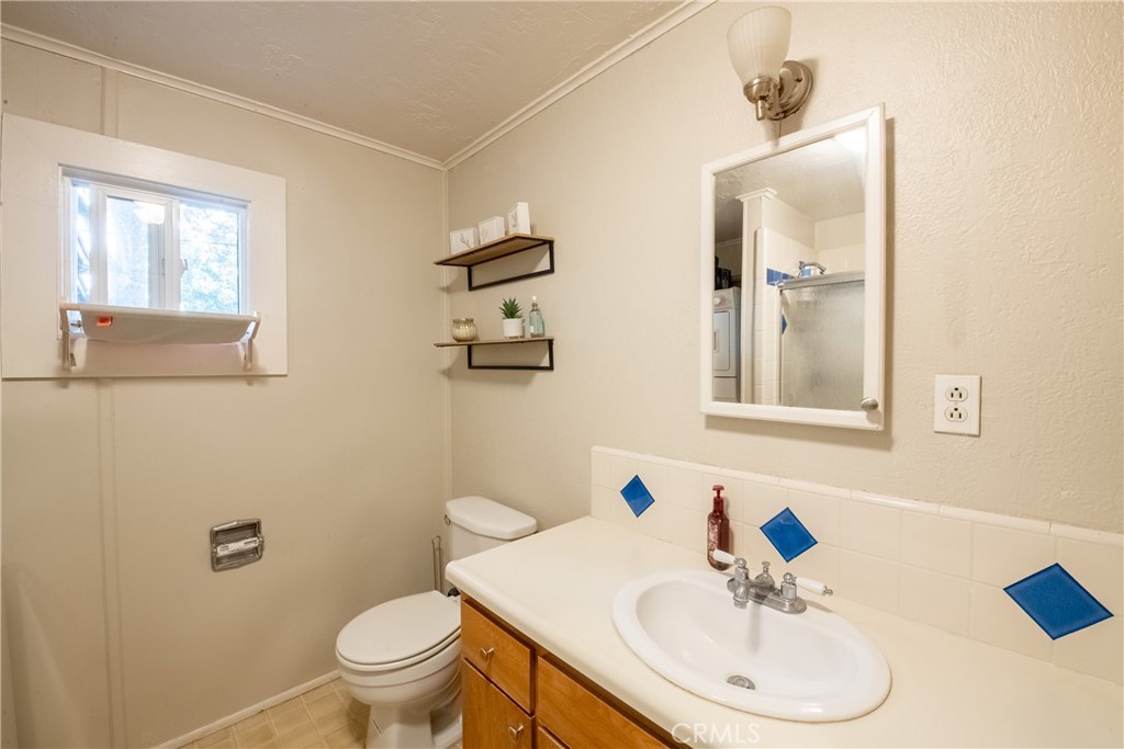 Bathroom with a wood vanity, white sink, blue accent tiles, and a window.