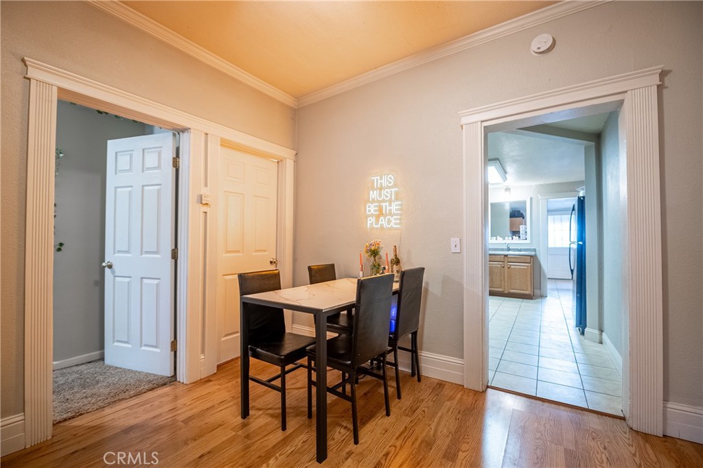 Furnished dining room with hardwood floors, a black table and chairs, and a doorway to the tiled kitchen.
