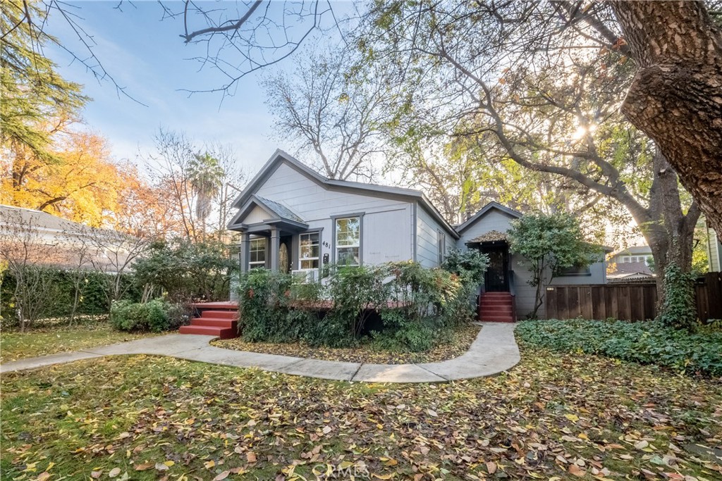Gray house with red entry steps, a curved walkway, and mature autumn trees.