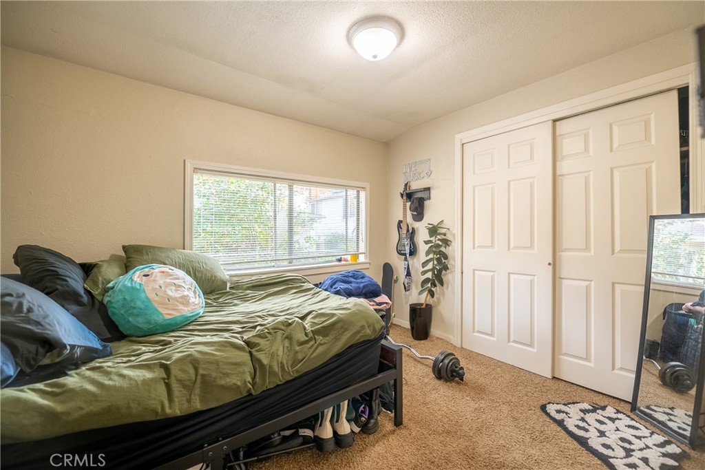 Bedroom with olive-green bedding, a wide window, and white sliding closet doors.