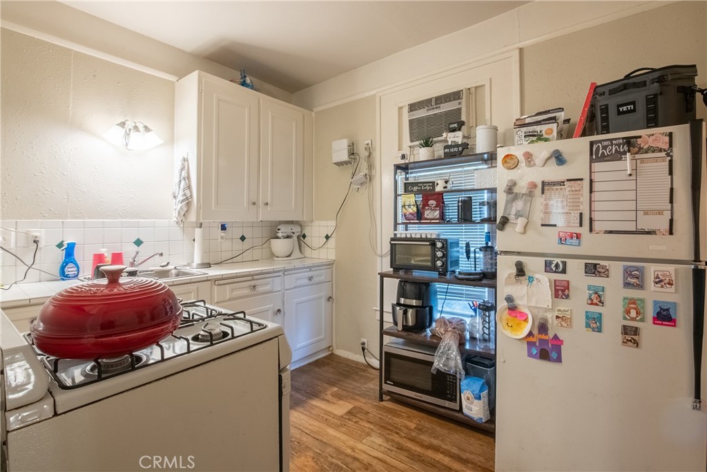 Kitchen with white cabinets, a red Dutch oven on the stove, and a refrigerator covered with magnets and notes.