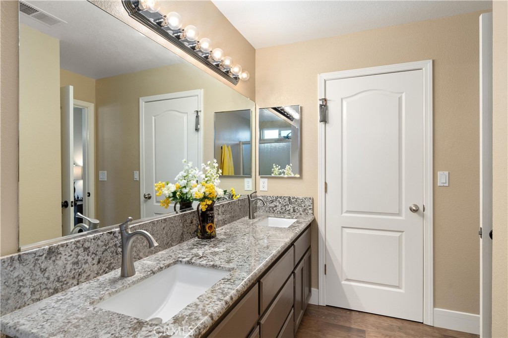 Bathroom vanity with patterned stone counters, dark wood cabinets, and a vase of flowers.