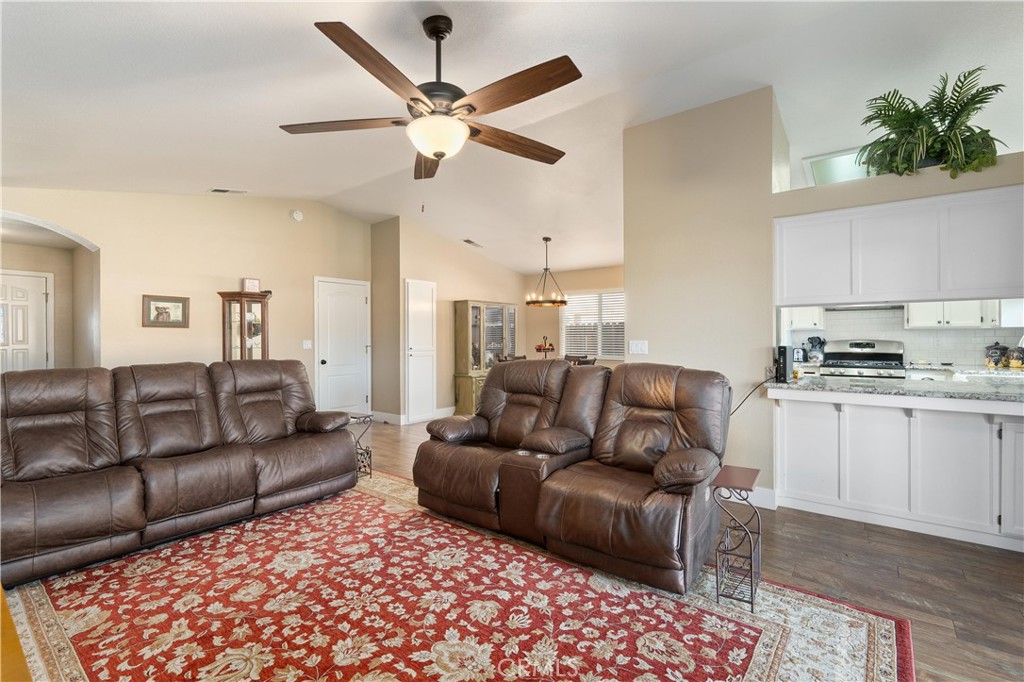 Living room with brown leather reclining sofas, a red floral rug, and an adjoining white kitchen.
