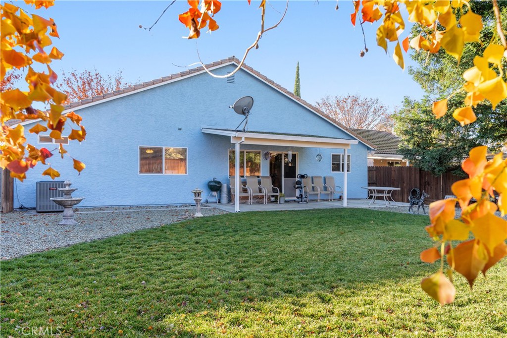 Blue house with covered patio and outdoor seating overlooking a lawn framed by autumn leaves.