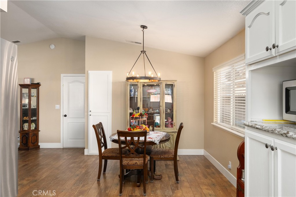Dining area with a round table, chandelier, hardwood floors, and glass-front display cabinets.