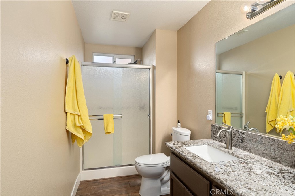 Bathroom with glass shower, granite vanity, and yellow towels.