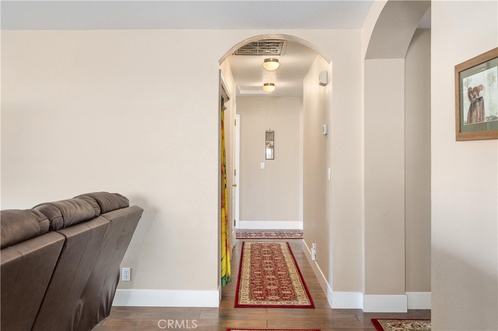 Hallway with an arched opening, wood floors, and red patterned runner rugs.