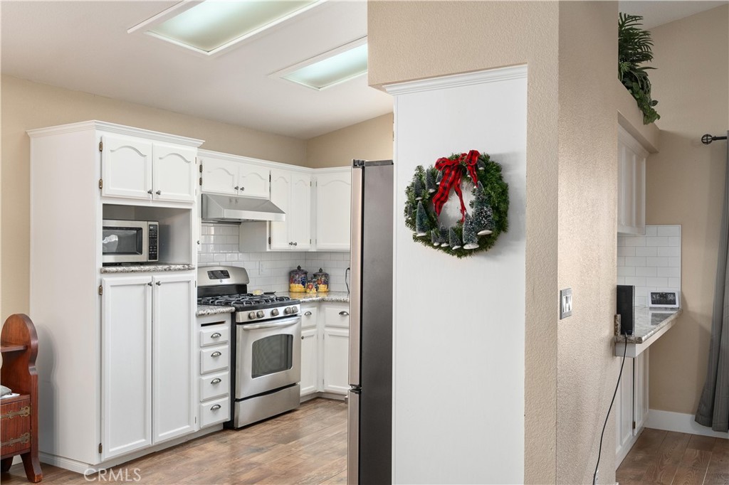 Kitchen with white cabinets, stainless steel appliances, and a holiday wreath on the dividing wall.