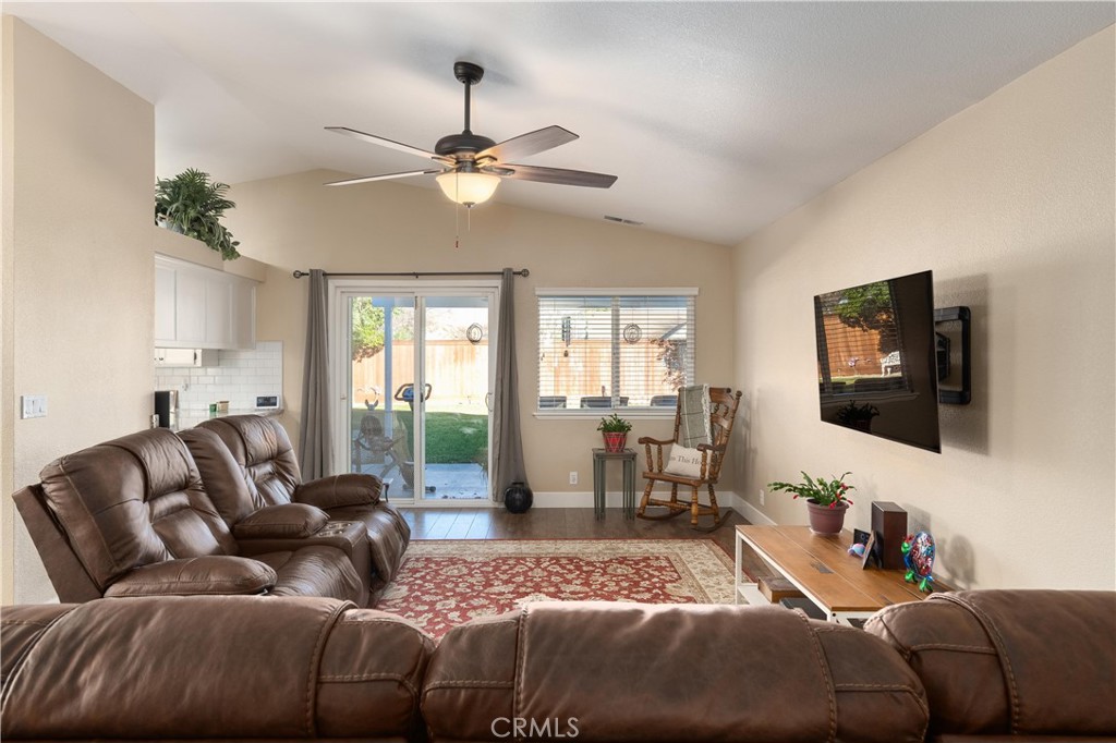 Living room with brown leather sofas, a ceiling fan, and sliding glass doors to the backyard.