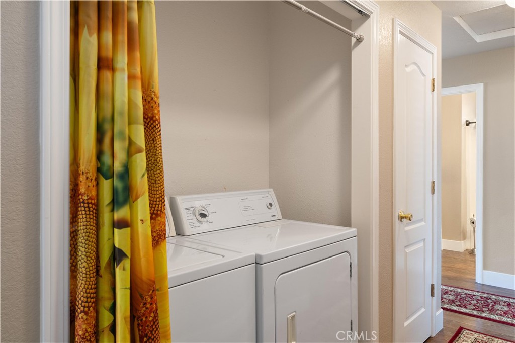 Laundry area with white washer and dryer partly screened by a colorful curtain.