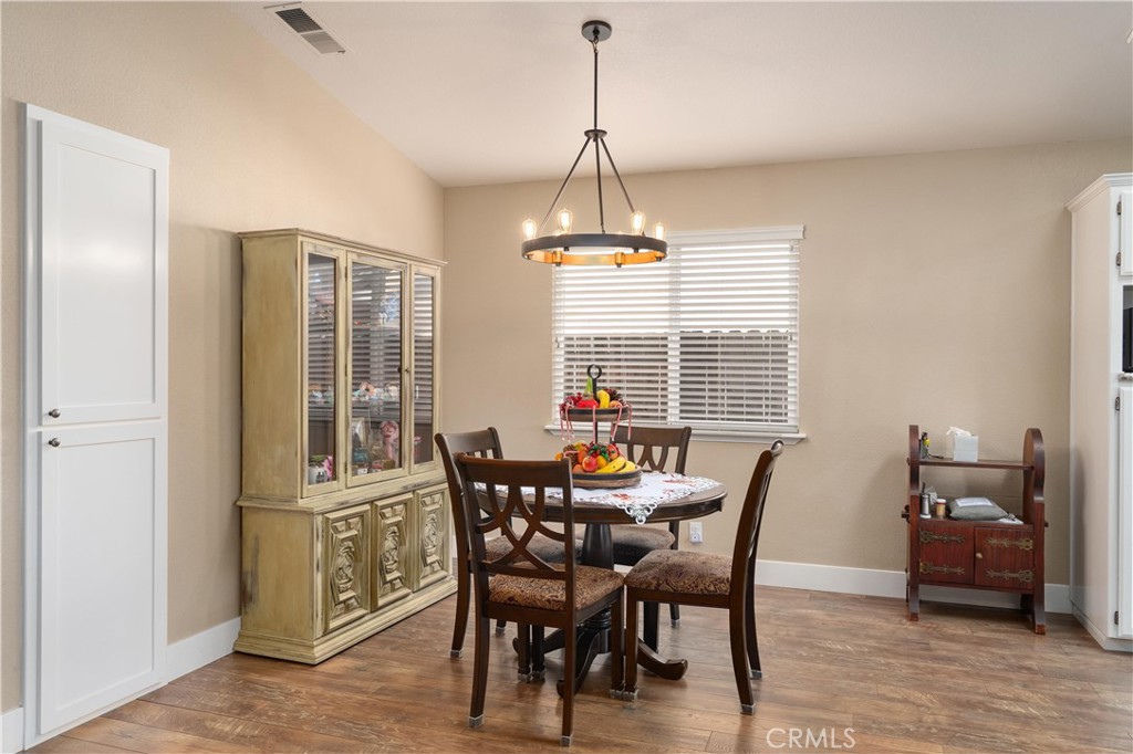 Dining room with a dark wood table, ornate china cabinet, and pendant chandelier.
