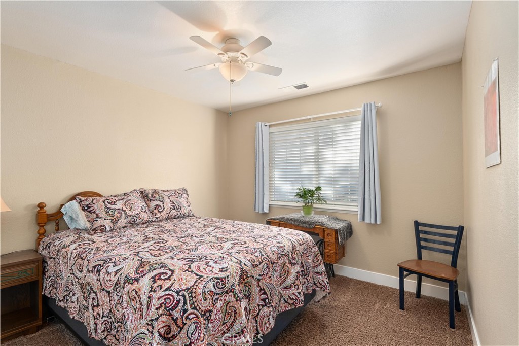 Bedroom with a paisley-covered wooden bed, ceiling fan, and window with blinds.