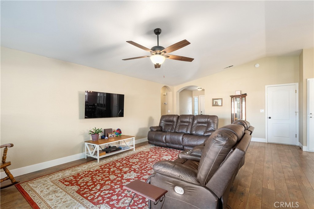 Living room with brown leather reclining sofas, a red patterned rug, and a wall-mounted television.