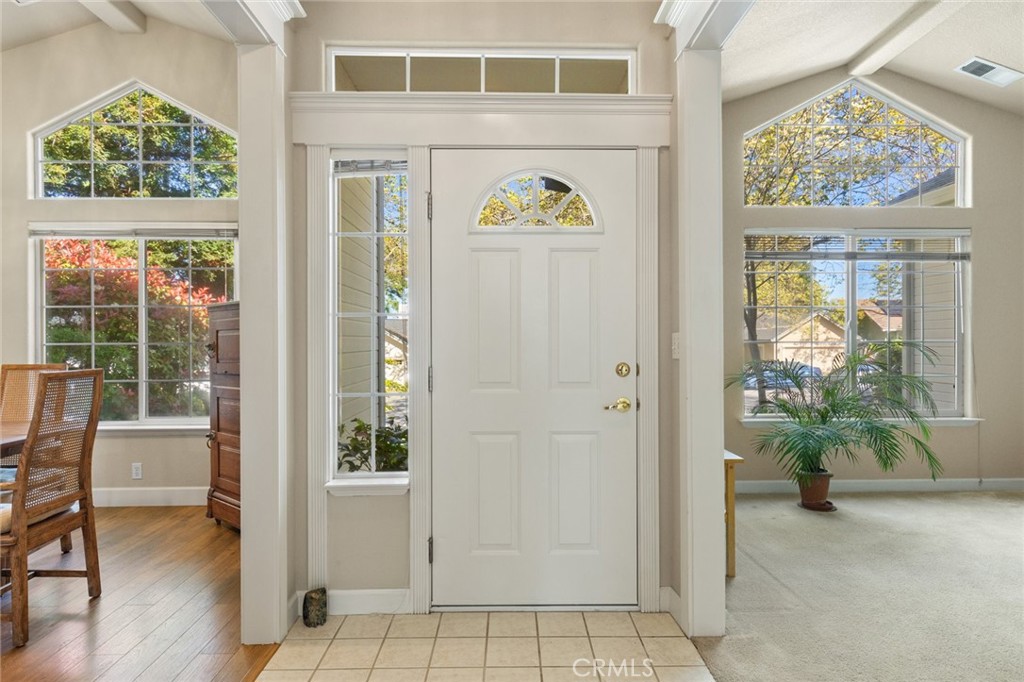 Entry foyer with a white front door, arched windows, and adjoining rooms.