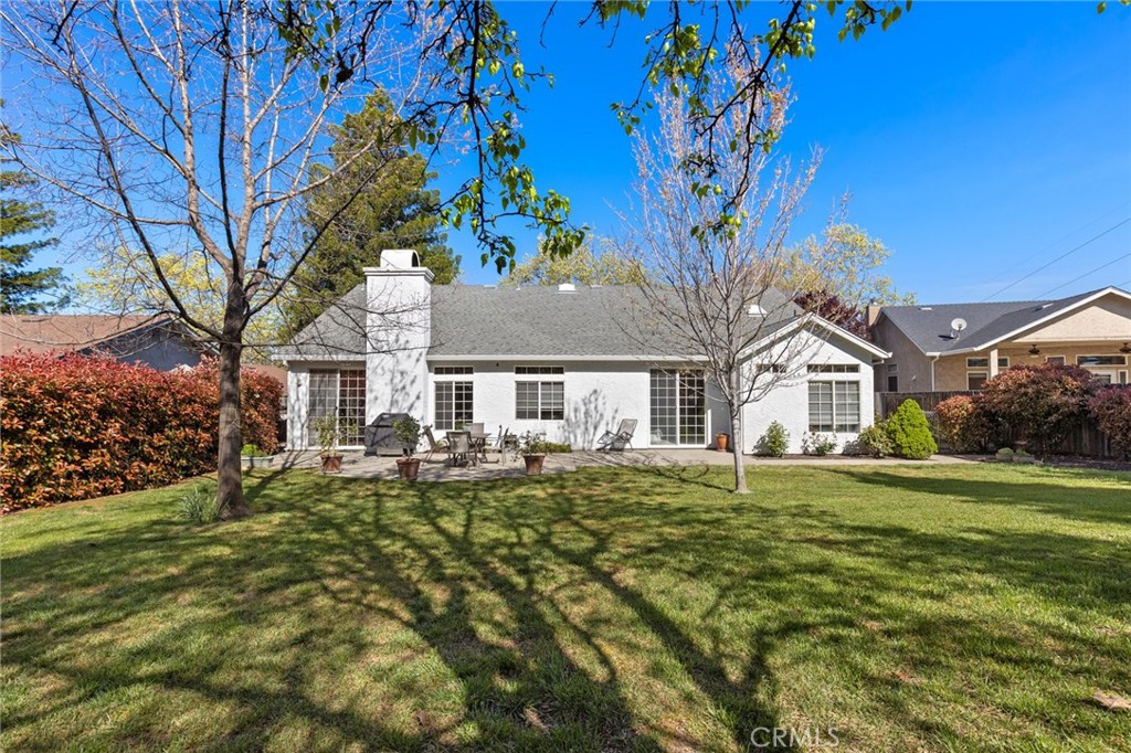 Rear exterior of a white single-story home with patio furniture and a broad lawn.