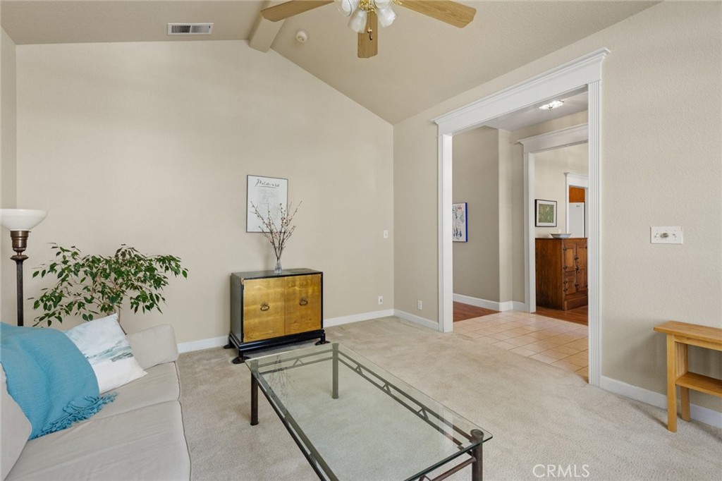 Living room with a glass coffee table and wide doorway to a tiled adjoining room.