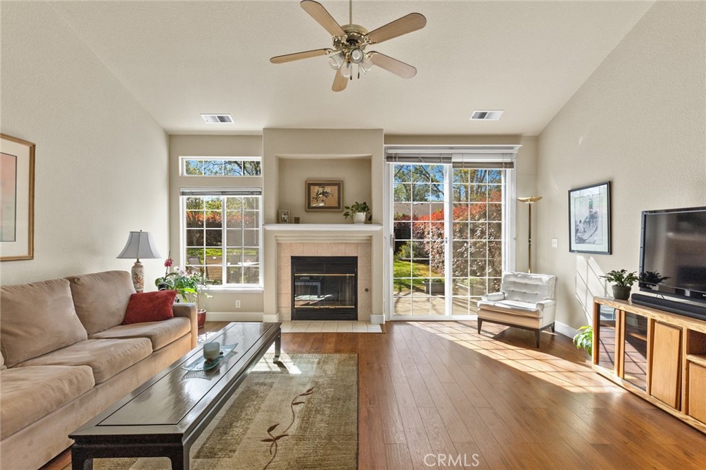 Living room with a fireplace, beige sofa, and sliding glass doors overlooking the yard.