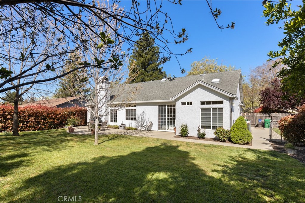 Rear of a white home with a gray gabled roof, patio, and landscaped backyard.