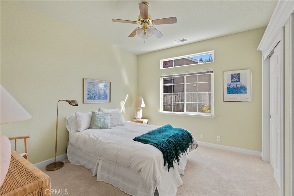 Staged bedroom with a white bed, teal throw, and large window.