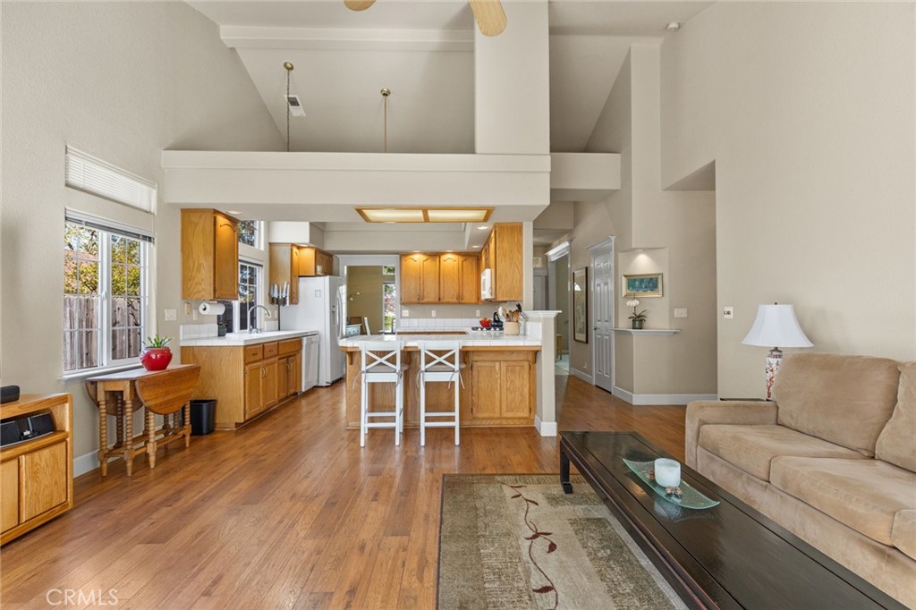 Open kitchen and living room with a wood-front island, honey-toned cabinets, and beige sofa.
