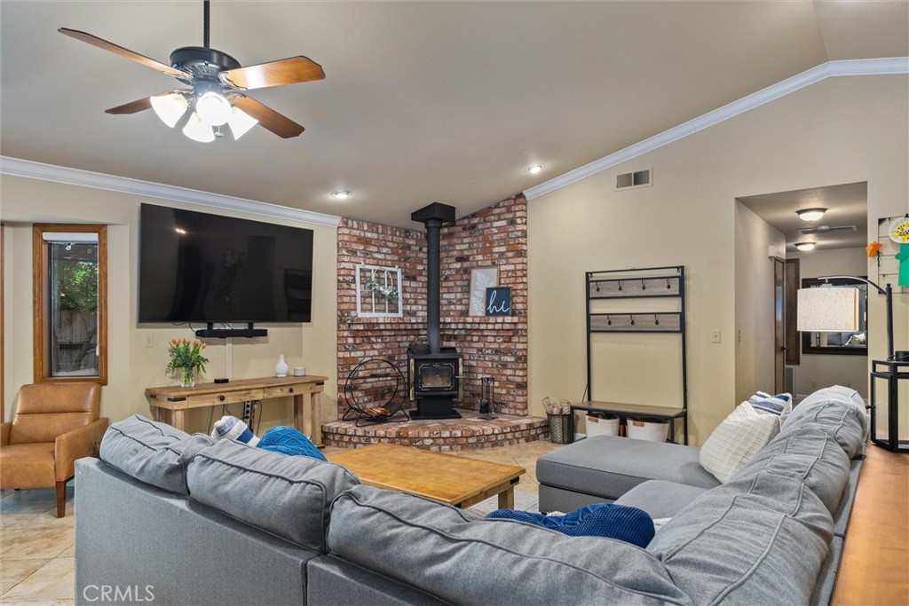 Living room with a gray sectional sofa, brick hearth, wood stove, and wall-mounted television.
