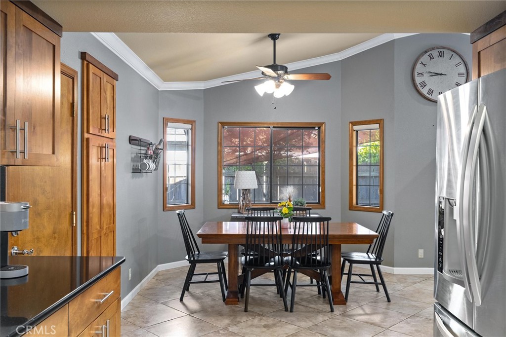 Dining area with a wooden table, black chairs, wood cabinets, and stainless steel refrigerator.