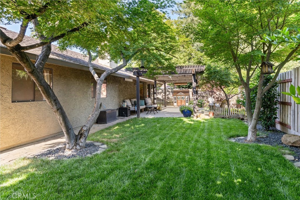 Backyard with a broad lawn, mature shade trees, a pergola, and outdoor seating.