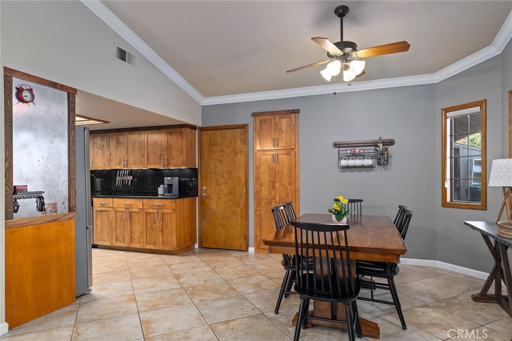 Dining area with a wooden table beside a kitchen with wood cabinets and black countertops.
