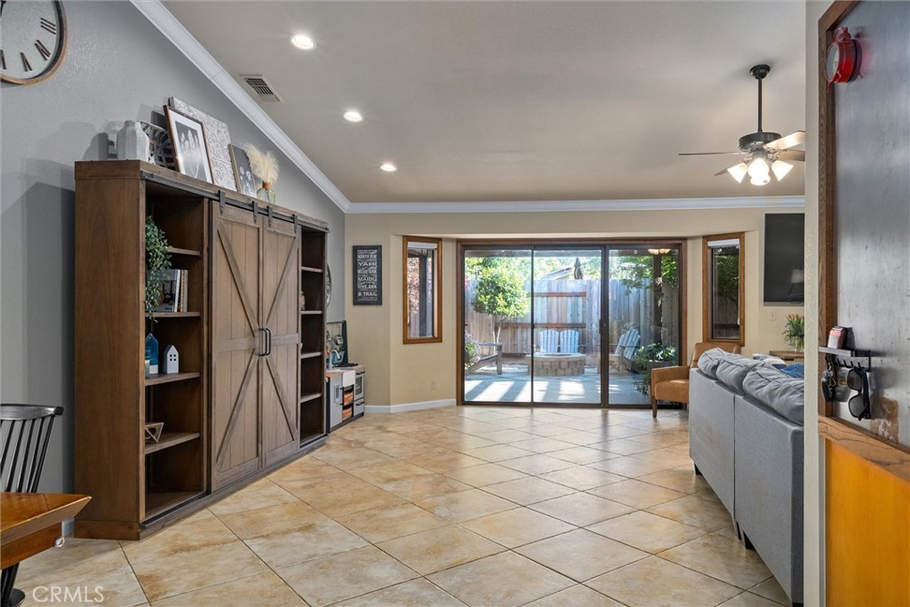 Living room with tile floors, a barn-door cabinet, gray sofa, and sliding glass doors to a patio.