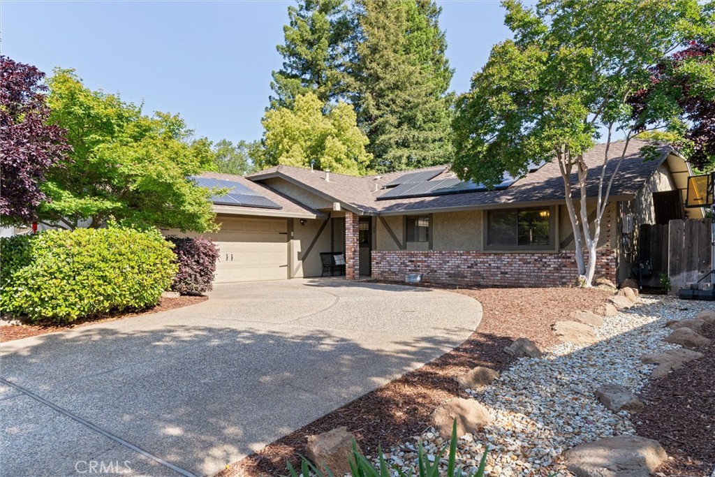 Single-story home with solar panels, a brick facade, and a curved driveway.