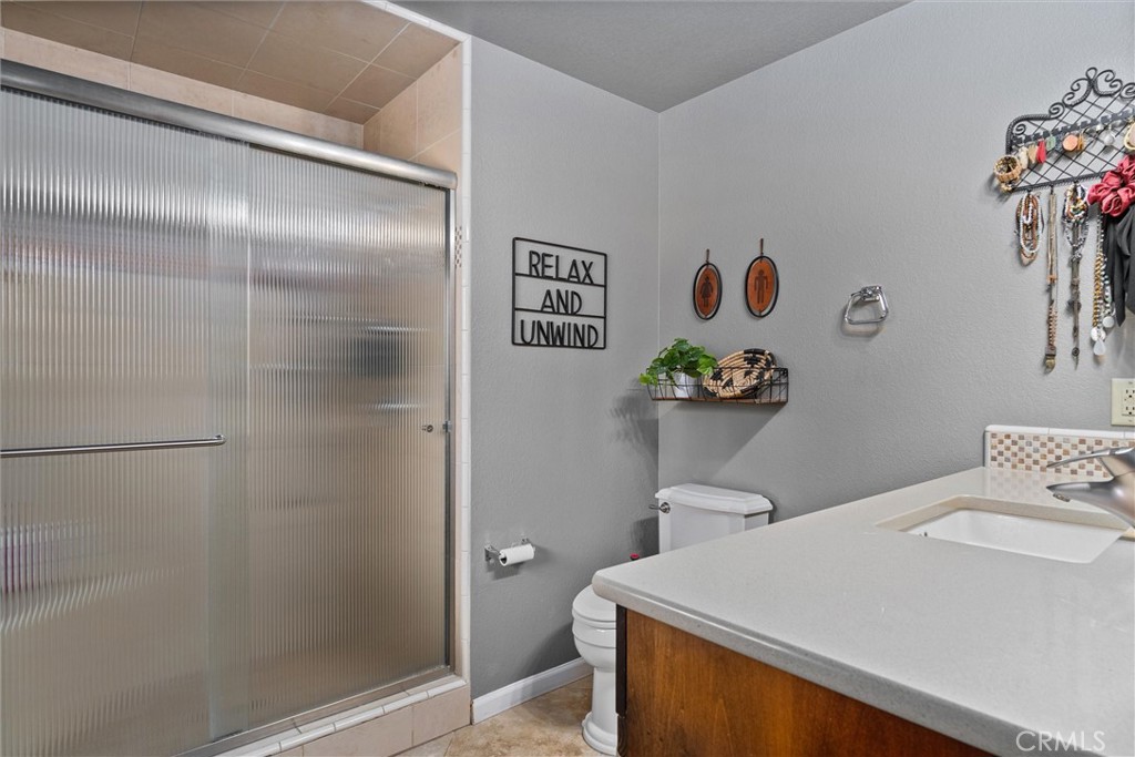 Bathroom with a frosted-glass shower, white countertop, and wood vanity.