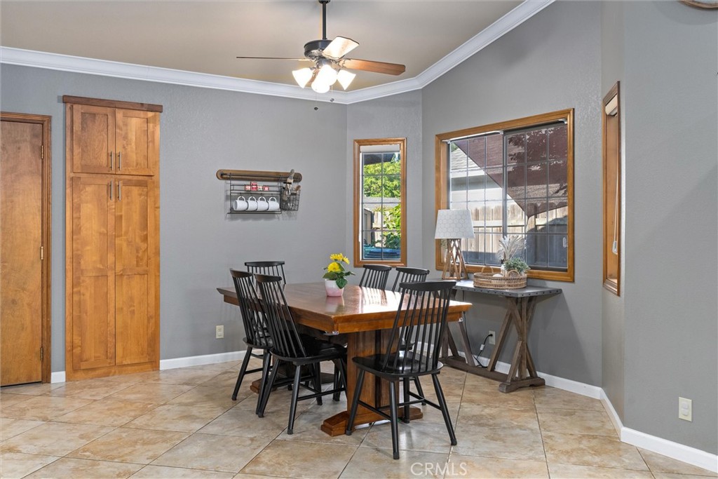 Dining room with a wood table, black chairs, tan tile flooring, and wooden cabinets.