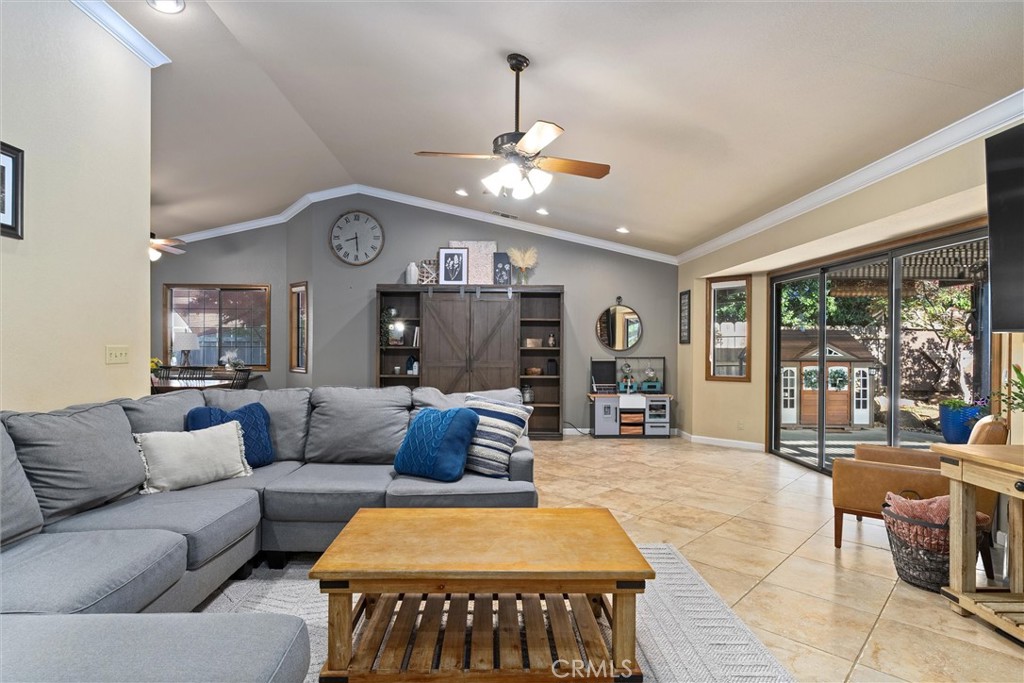 Living room with a gray sectional, vaulted ceiling, and sliding glass doors to a patio.