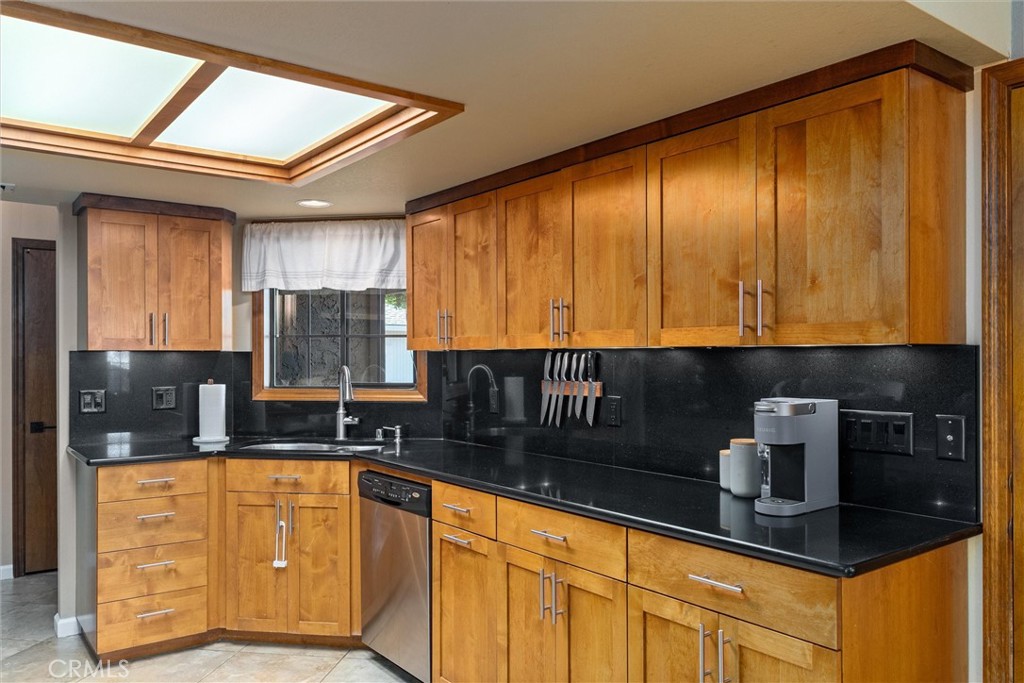 Kitchen with extensive warm wood cabinetry, black counters, and a geometric ceiling light.