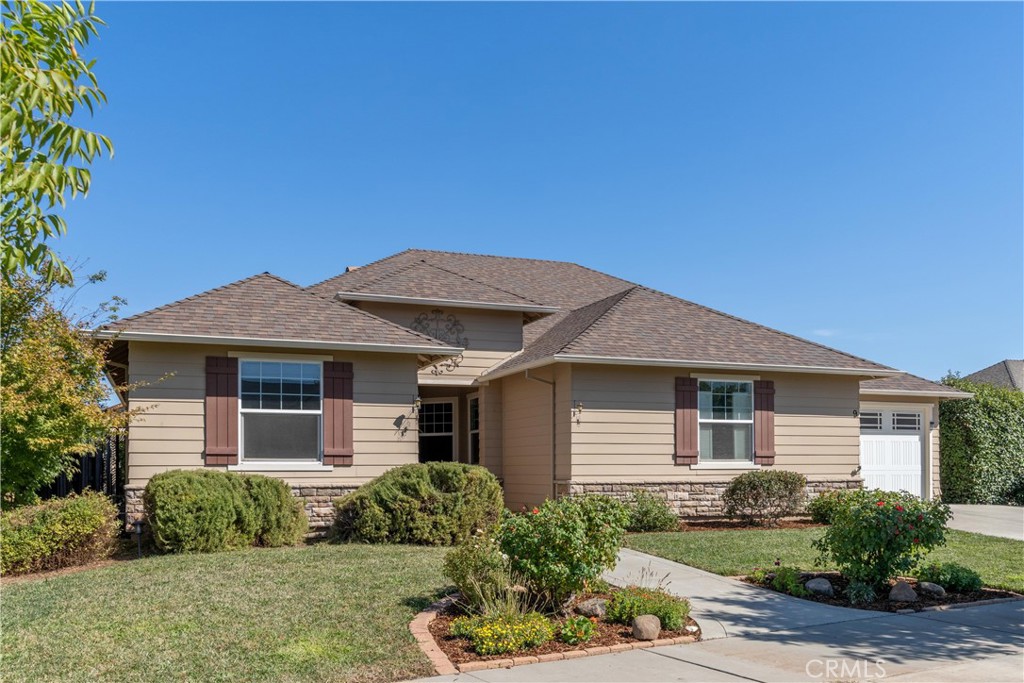 Single-story beige home with burgundy shutters, stone veneer, and a landscaped front yard.