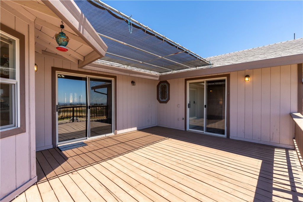 Covered wooden deck with an overhead shade canopy and sliding glass doors.
