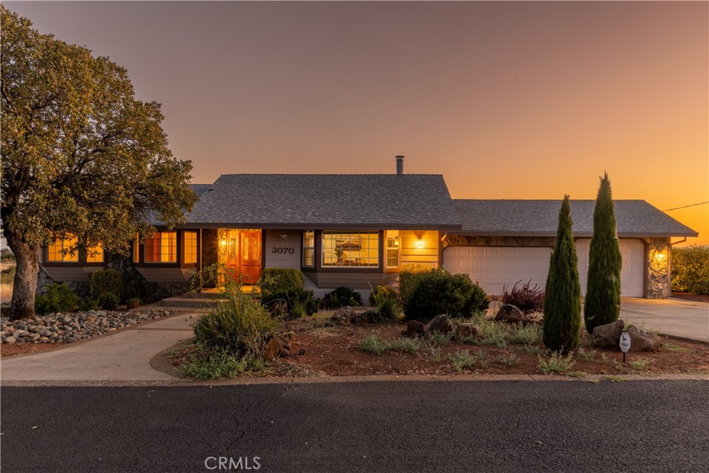 Single-story home with a stone-accented facade and warm windows at sunset.