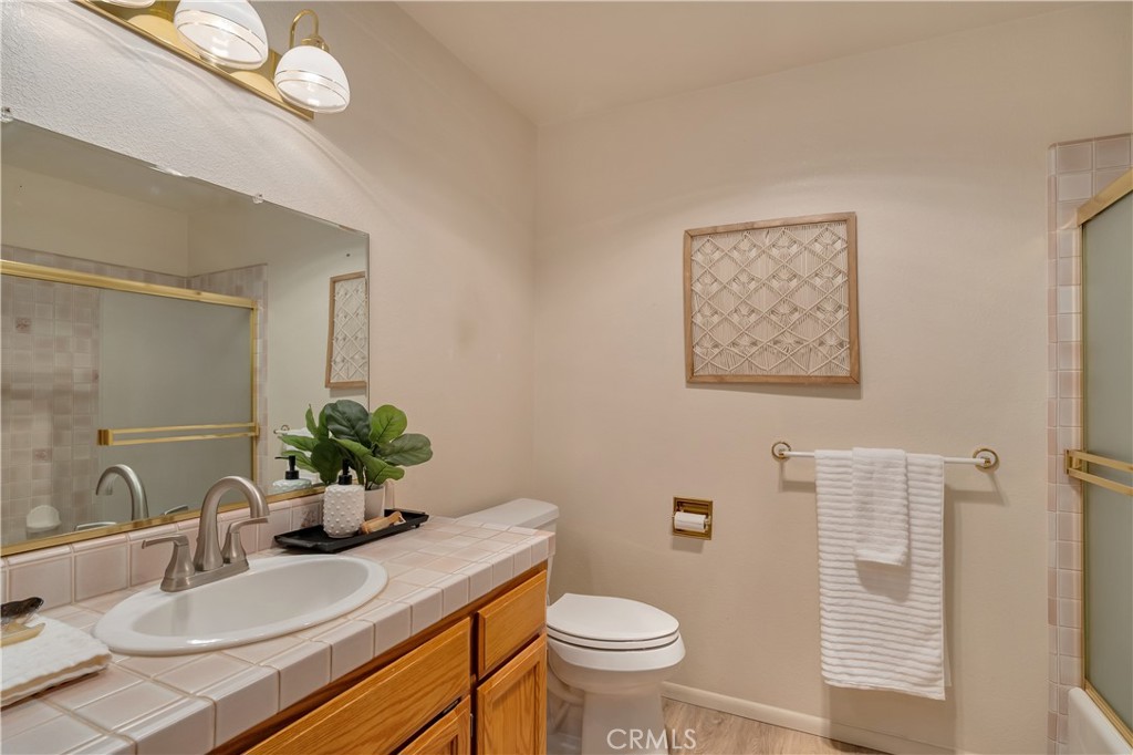 Bathroom with a tiled vanity, wood cabinets, glass shower, and framed woven wall decoration.