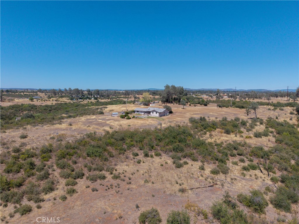 Single-story home surrounded by dry open acreage and scrub, viewed from above.