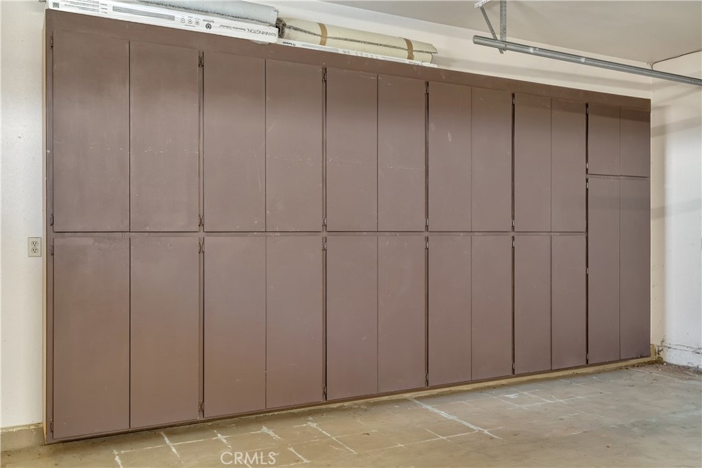 Garage with a long wall of brown storage cabinets and a concrete floor.