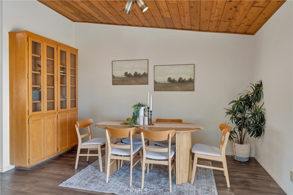 Dining room with a round wooden table, six chairs, built-in cabinet, and wood ceiling.