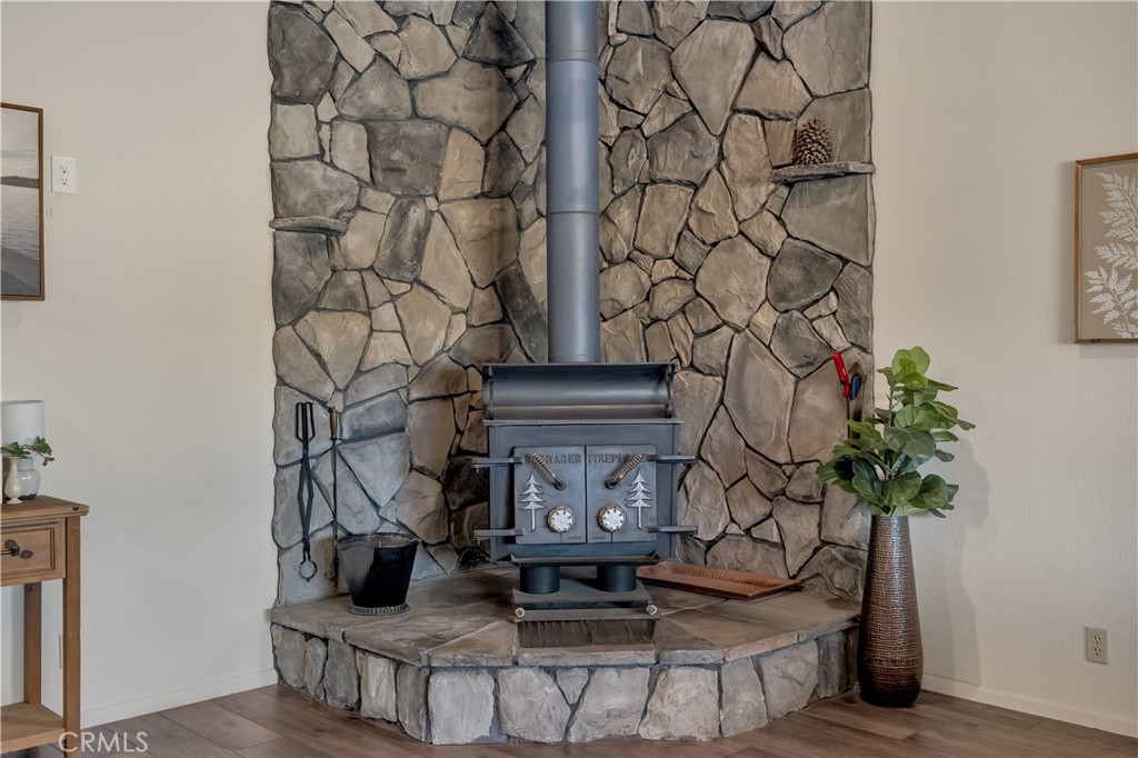 Living room with a freestanding wood stove against a floor-to-ceiling stone fireplace.