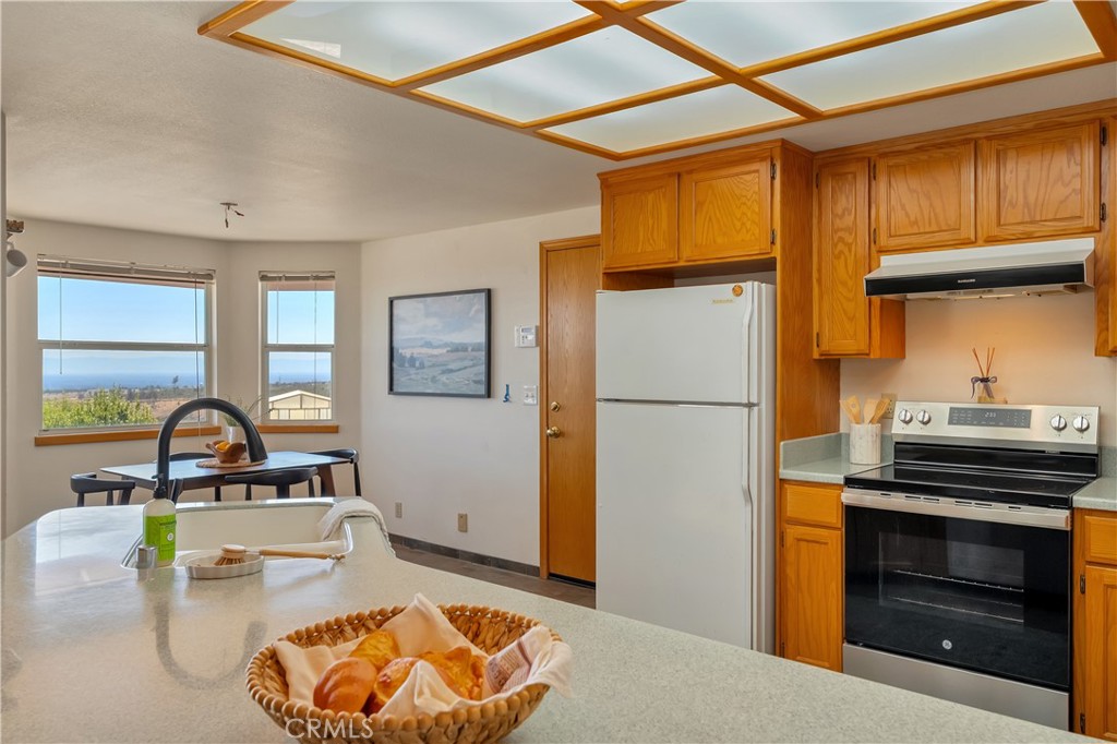 Kitchen with warm wood cabinets, a peninsula sink, and windows overlooking a distant landscape.