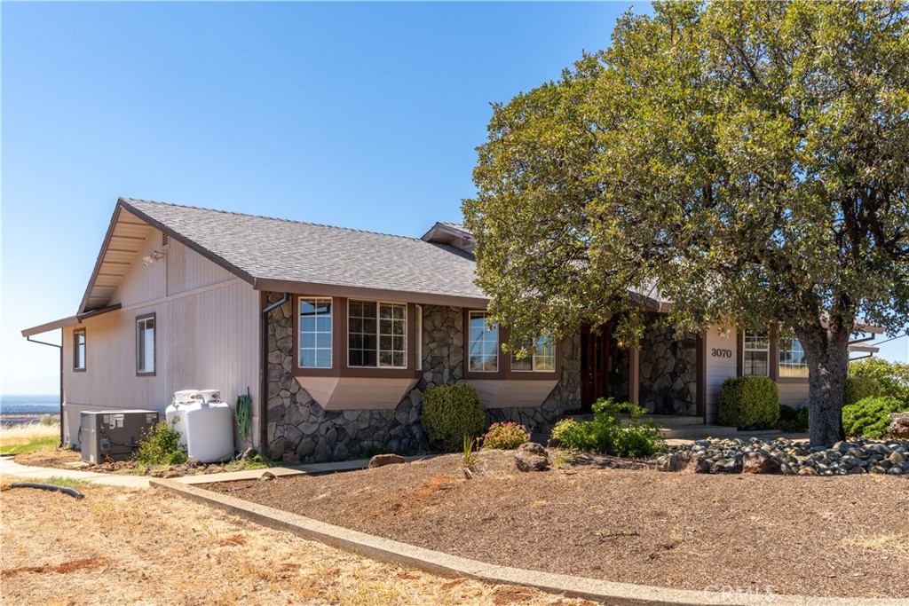 Single-story home with a stone facade and a large tree shading the front entrance.