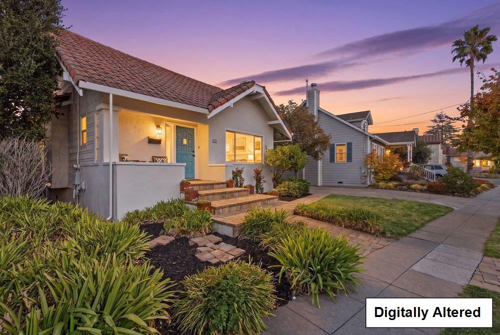 Gray cottage with a teal front door and landscaped entry at dusk.
