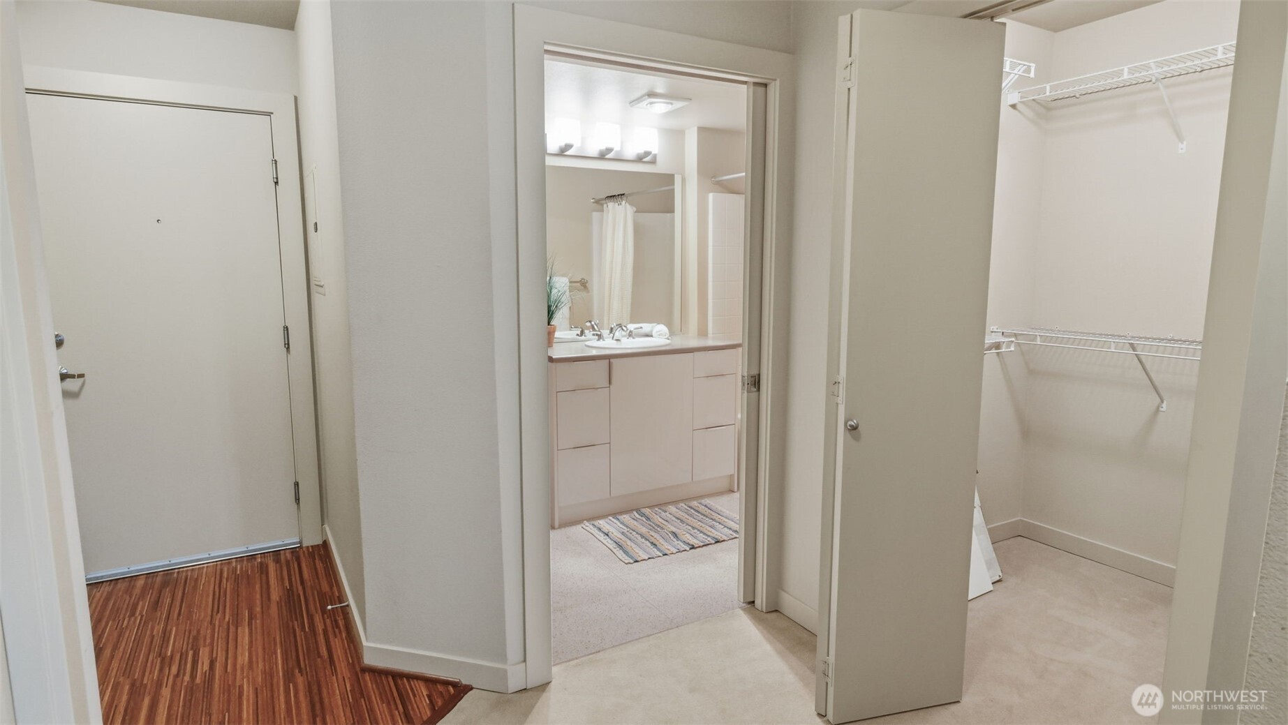 Condominium entry hall with an open bathroom vanity and walk-in closet with wire shelving.
