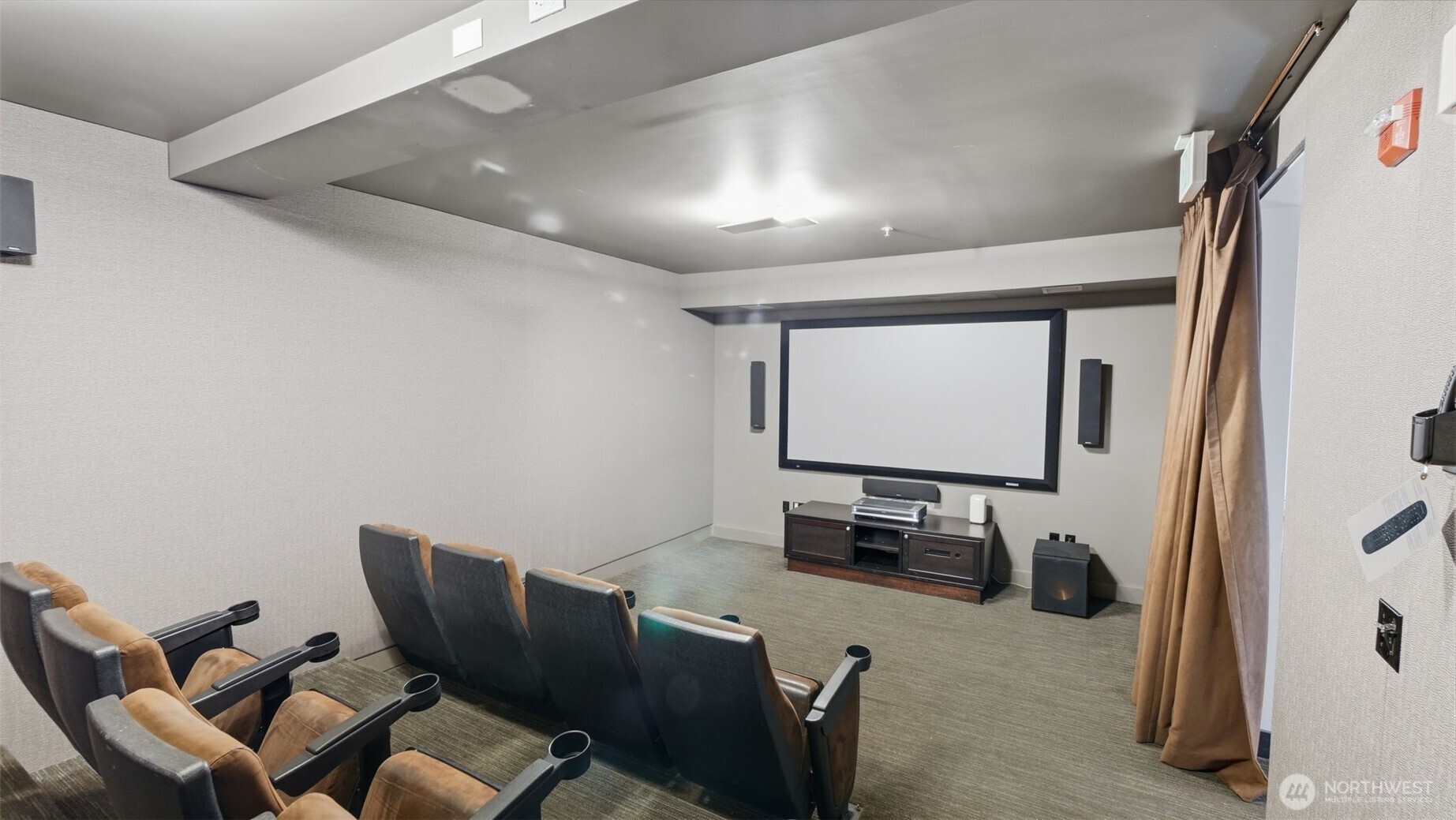 Furnished theater room with rows of cushioned seats facing a large projection screen.