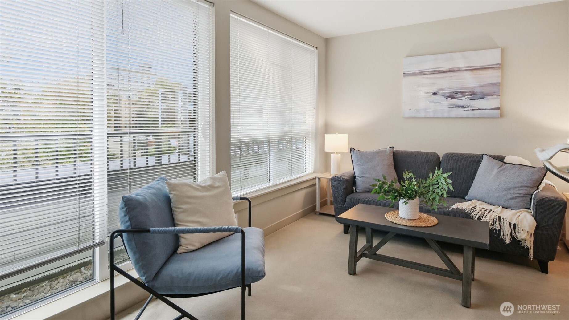 Living room with large windows, a gray sofa, and a blue armchair.