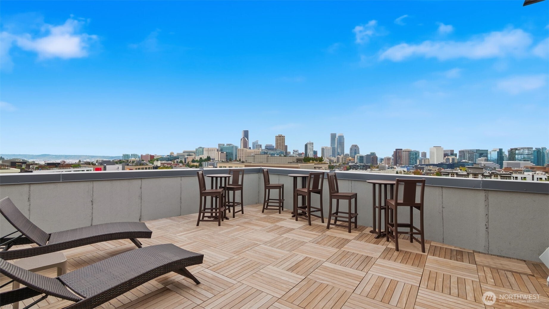 Rooftop deck with lounge chairs and bar tables overlooking the Seattle skyline.